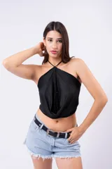 Top negro ajustado con escote drapeado tipo cowl neck y cuello halter. La tela presenta pequeños apliques brillantes distribuidos por toda la superficie.