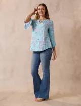 Blusa de seda fría estampada con flores en tonos celeste, lila y verde. Tiene cuello redondo con escote en V entrelazado y mangas 3/4 acampanadas.