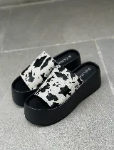 Sandalias tipo sueco con plataforma de goma negra y tira ancha de cuero con estampado animal print de vaca.
