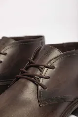 Bota de cuero marrón oscuro con cordones, suela de goma y diseño clásico.