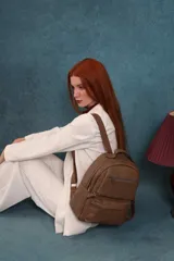 Mochila color marrón de símil cuero con un compartimento principal amplio, bolsillo al frente con cierre, correas ajustables y asa.