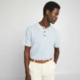 Remera tipo polo celeste de punto con cuello clásico y tres botones marrones.