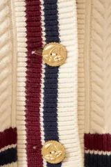 Cardigan celeste de punto trenzado, con escote en V y botones metálicos. Presenta ribetes a contraste en cuello, puños y bajo.