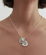 Collar plateado con cadena de eslabones y dije en forma de corazón con detalles ornamentales y una piedra en el centro.