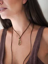 Gargantilla marrón de cuero con dije de bronce en forma de letra M.