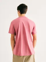 Camiseta blanca de algodón con cuello redondo y mangas cortas. Estampa rectangular con borde negro que contiene la frase "NATURAL ATMOSPHERE" en letras mayúsculas y una imagen de montañas y mar.