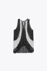 Top de cuello redondo y manga sisa con detalle de tejido plisado semitransparente y estampado de lunares blancos y negros. Bajo asimétrico y cierre en espalda con abertura y botón.
