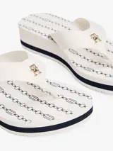 Ojotas de mujer con plataforma de cuña, tiras anchas de tejido trenzado y monograma TH en la tira del dedo. La plataforma es blanca con una línea decorativa azul marino.