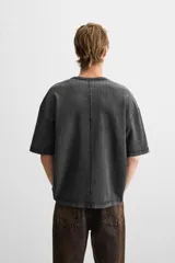 Camiseta color gris verdoso de punto tejido en hilatura de algodón, con cuello redondo, manga corta, efecto lavado y acabados irregulares.