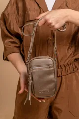 Bandolera compacta de símil cuero color rojo, con correa regulable y desmontable. Posee apertura superior, bolsillo frontal con cierre y bolsillo trasero abierto.