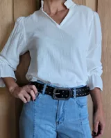 Cinto marrón de cuero con tachas plateadas y doradas, y hebilla metálica rectangular color bronce.