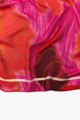 Pañuelo cuadrado de modal y seda con estampado de amapolas en tonos rojos y fucsias, y borde blanco.