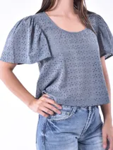 Blusa color blanco con mangas cortas abullonadas y calado con pequeños orificios.