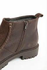 Bota de cuero color marrón con diseño que combina texturas de cuero liso y gamuza. Cuenta con suela de goma tipo track, cierre lateral para facilitar el calce y tirador trasero.