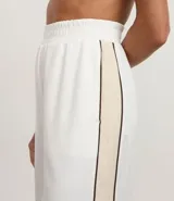 Pantalón deportivo blanco de tiro alto, corte ancho y pierna recta, con friso lateral contrastante.