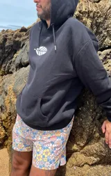 Hoodie negro de corte oversize con cordones ajustables y estampado frontal de una hoja blanca.