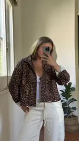 Campera corta de pana con estampado de leopardo, cuello camisero, cierre frontal con botones a presión y dos bolsillos delanteros. Interior forrado con tela a rayas verticales.