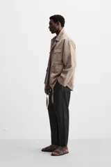 Pantalón de lino color marrón oscuro, de corte recto y relaxed fit. Tiene cintura elástica ajustable con cordón, bolsillos frontales y traseros de parche.