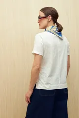 Remera blanca de algodón liviano con textura sutil, manga corta y cuello redondo.