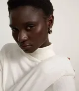 Blusa de punto color blanco, con cuello alto, manga larga y diseño liso.