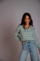 Sweater de punto color beige con rayas horizontales blancas, cuello polo con cierre de cremallera y mangas largas.