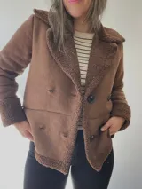 Chaqueta marrón con forro tipo corderito, doble botonadura y cuello con solapas.