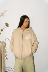 Hoodie con cierre frontal de algodón color crema con lavado acid wash. Presenta un logo estilizado en el pecho y estampados gráficos con caracteres orientales en ambas mangas.