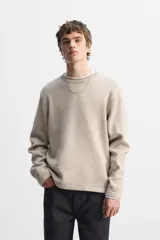 Jersey color beige de punto con cuello redondo y manga larga.