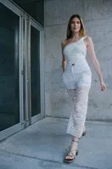 Pantalón de encaje blanco con viso blanco y cinto con hebilla dorada.