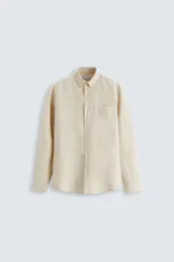 Camisa celeste a rayas verticales, de corte relaxed fit, confeccionada en lino y algodón. Tiene cuello abotonado, manga larga con puños abotonados, bolsillo de parche en el pecho y cierre frontal con botones.