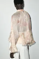 Camisa de cuello subido y manga larga con estampado floral en tonos rosa y verde. Detalle de volantes en cuello, mangas y ruedo. Cierre en espalda con abertura y botones.