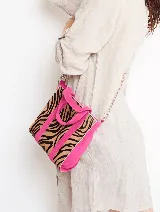Bolso tipo tote con estampado de cebra en tonos marrones y negros, detalles en color fucsia y correa de cadena metálica.