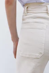 Pantalón de jean de tiro alto color negro con pierna ancha, bolsillos delanteros y traseros, y cierre frontal con cremallera y botón metálico.