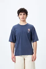 Remera azul con efecto gastado, corte holgado y estampado pequeño de flor en el pecho.