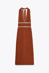 Vestido midi color ladrillo con escote en pico y tirantes anchos que se atan en la espalda. Presenta espalda descubierta, bordados blancos en contraste y frunces laterales en la cintura. La falda tiene una abertura en la parte trasera y el cierre es con cremallera oculta en la costura lateral.