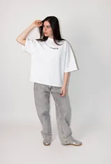 Remera blanca de corte amplio con cuello redondo y diseño minimalista en el pecho.