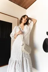 Bandolera rectangular de cuero color nude con doble compartimento con cierre de cremallera plateada y correa de cuero ajustable.