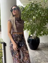 Falda larga de tela estampada con motivos florales en tonos marrones, negros y violetas. Tiene elástico en la cintura y corte acampanado.