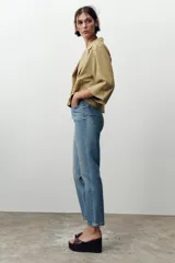Jeans de tiro alto color celeste, corte mom fit, con cinco bolsillos y cierre frontal con cremallera y botón.