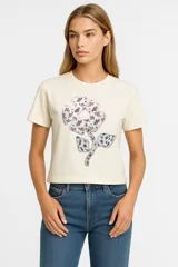Remera color crema de algodón con estampado de una flor multicolor.