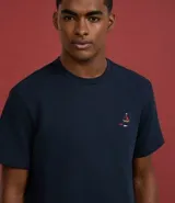 Remera de hombre color azul marino, corte regular, cuello redondo y manga corta. Presenta un pequeño bordado multicolor en el pecho que simula un barco y peces.
