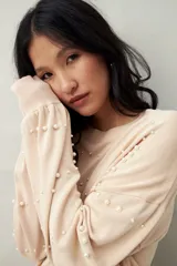 Sweater color beige con cuello redondo y mangas largas. Decorado con perlas sintéticas en forma de rombos.
