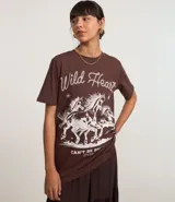 Remera blanca de algodón con cuello redondo y mangas cortas. Estampa frontal con diseño western de caballos y texto "Wild Heart".