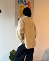 Camisa a rayas verticales amarillas y blancas, de corte holgado y mangas largas.