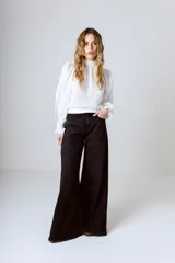 Blusa blanca de broderie con cuello alto, mangas largas abullonadas y puños elásticos.