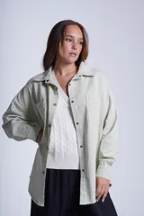 Sobrecamisa color beige de gabardina con cuello camisero, cierre frontal con botones a presión, dos bolsillos de parche en el pecho y corte holgado.