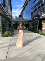 Falda midi color beige, de corte recto en la parte superior y con vuelo en la parte inferior.