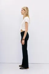 Pantalón jean de tiro medio, calce ajustado, con proceso de coating de acabado símil cuero y pierna levemente acampanada.