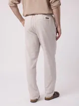 Pantalón largo de hombre, color beige con finas rayas verticales blancas, de corte recto y estilo pijamero.