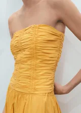 Top bandeau color amarillo con diseño fruncido, sin mangas y cierre de cremallera en la parte posterior.